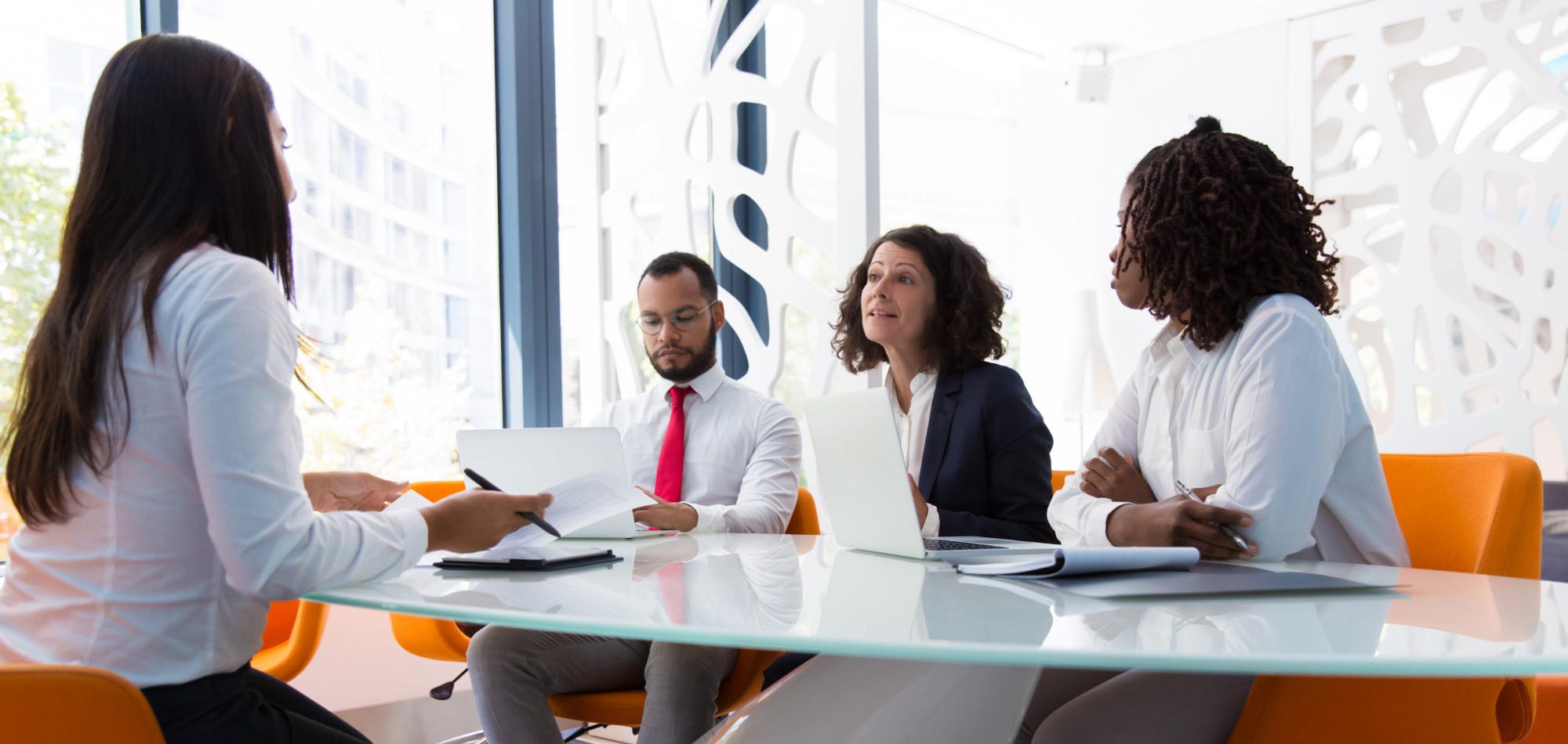 Young professional sitting in an office with three hiring managers for a job interview.